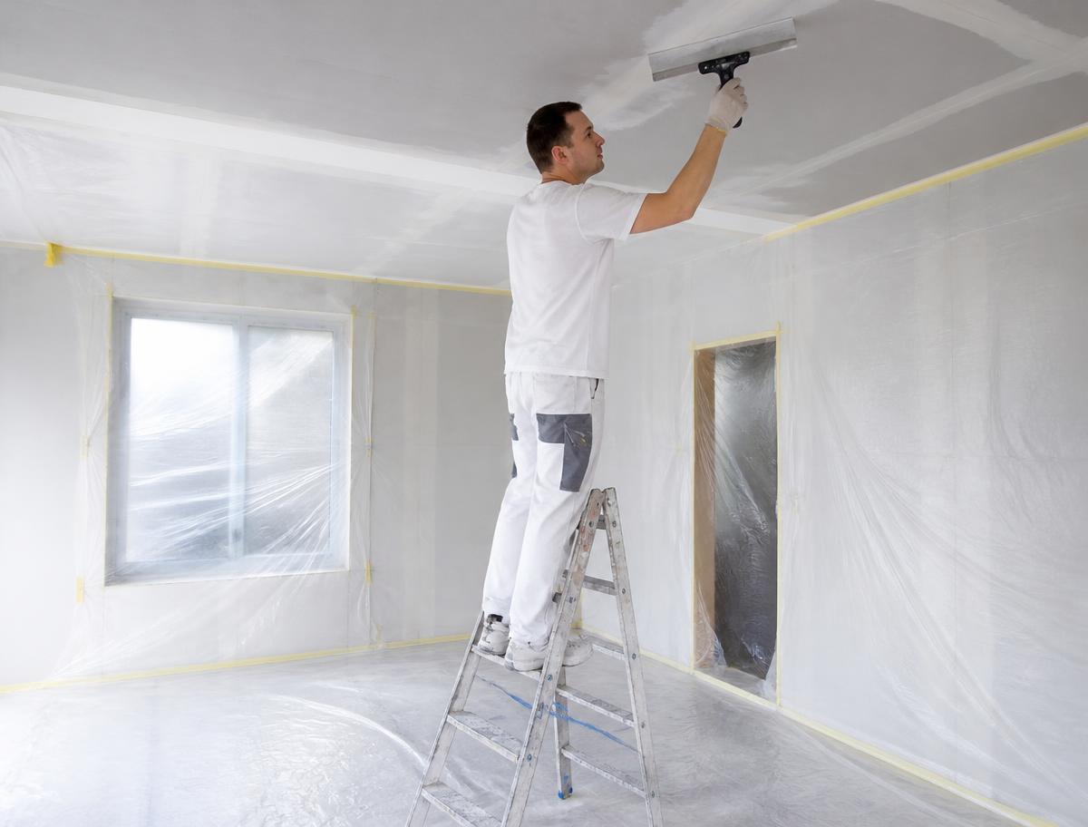 Protected room during ceiling preparation with skim coating and sanding in progress